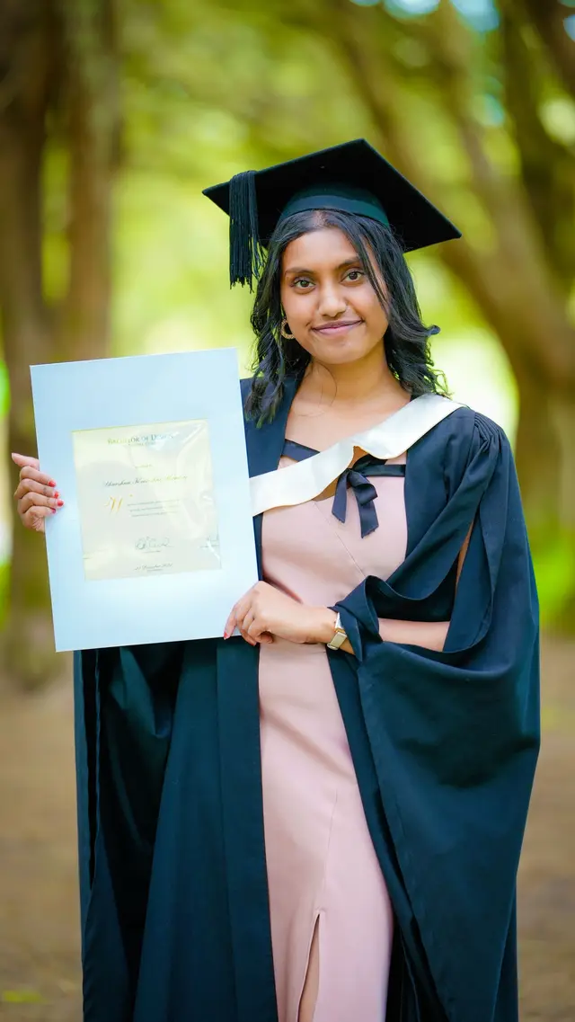 A graduate proudly holding her degree certificate