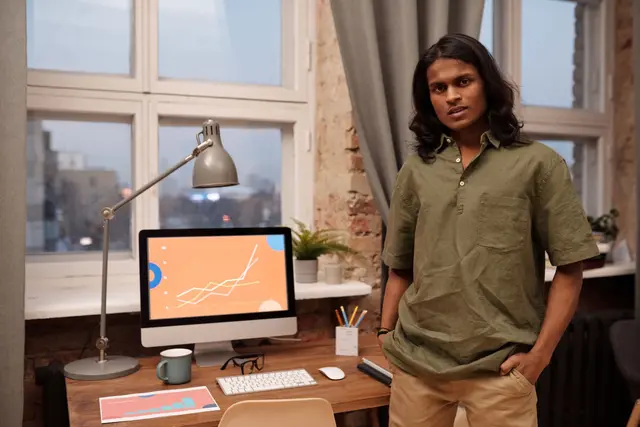 A young founder standing beside his desk and growth chart
